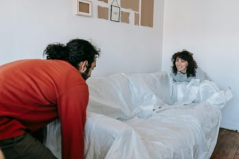 Two people lifting heavy furniture