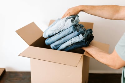 Person packing clothes in moving box