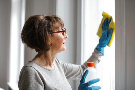 Elderly woman cleaning window 